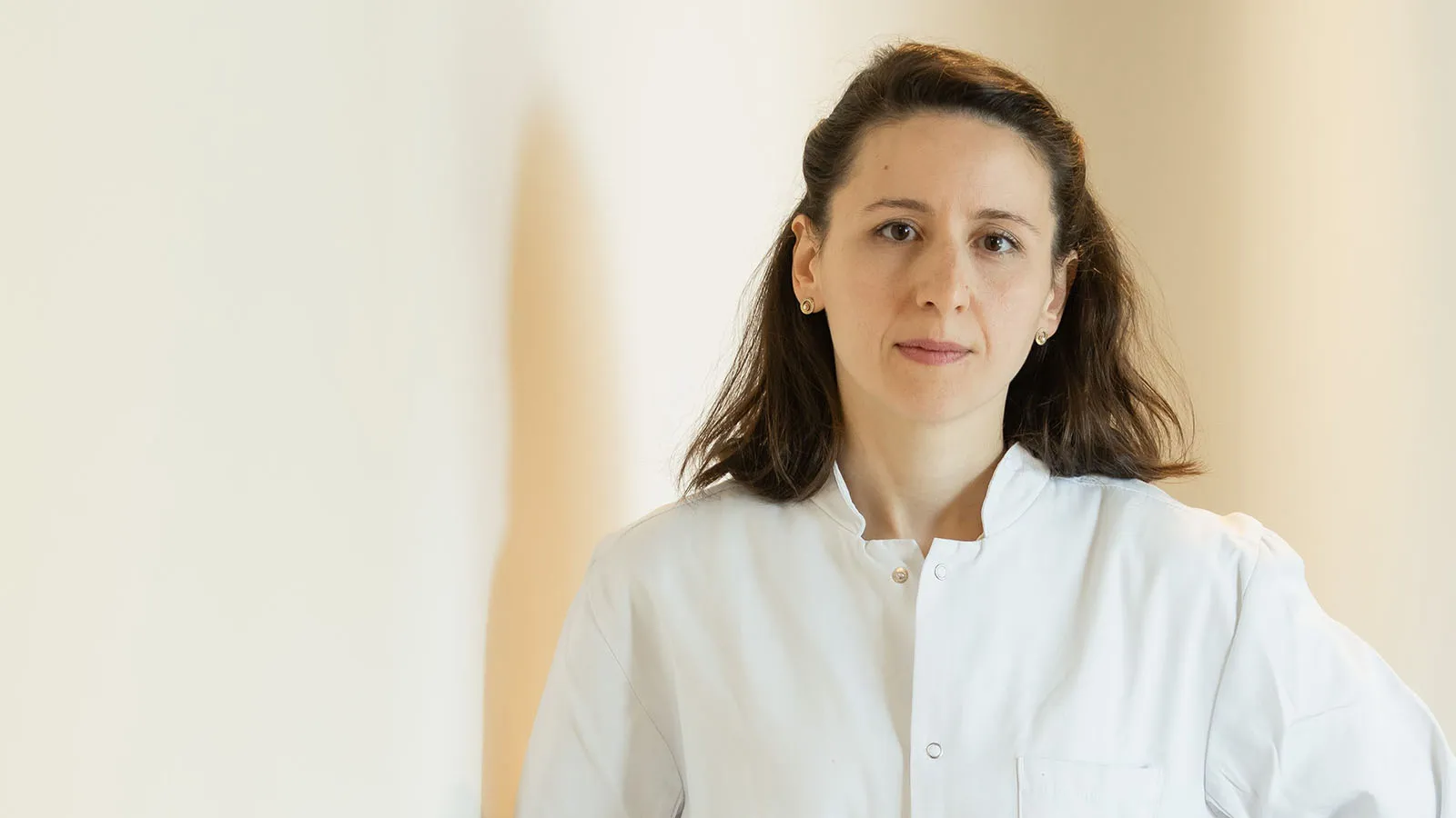 Ärztin im weißen Kittel sieht in die Kamera. Sterile Atmosphäre.