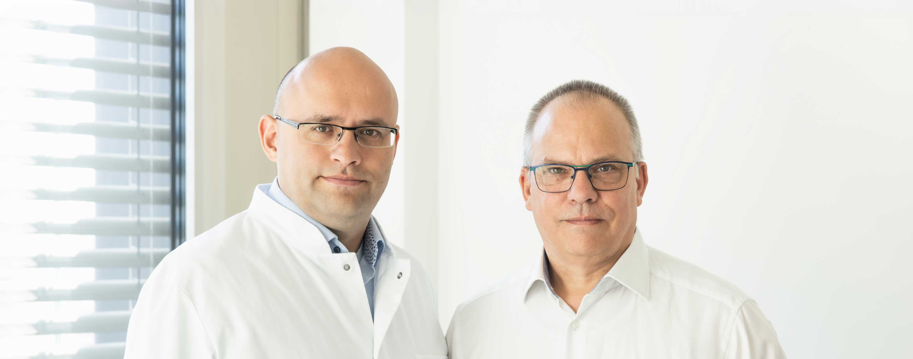 Die beiden Vorsitzenden des MB Nds Hammerschmidt und Wollenberg gucken in die Kamera, sterile Atmosphäre.